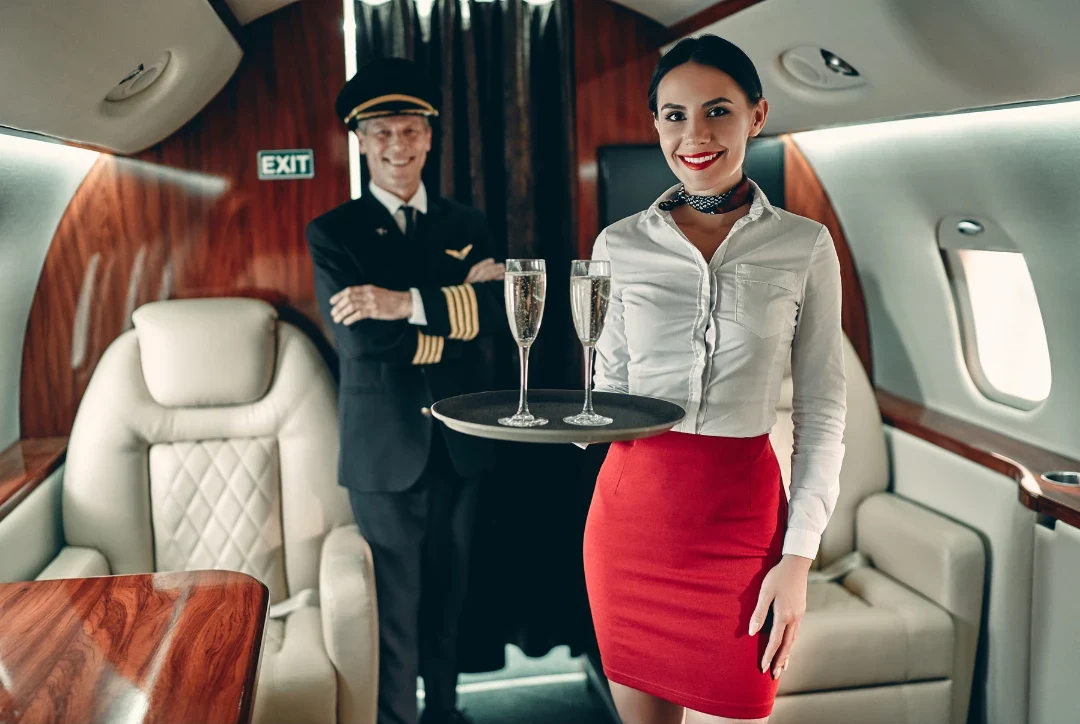A pilot and a flight attendant serving champagne in a private jet cabin